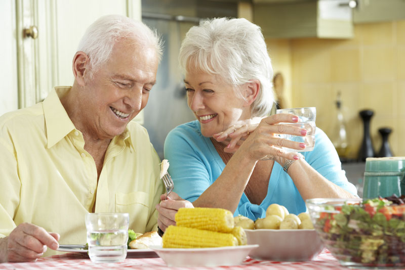 An image of an elderly couple smiling with implant supported dentures.