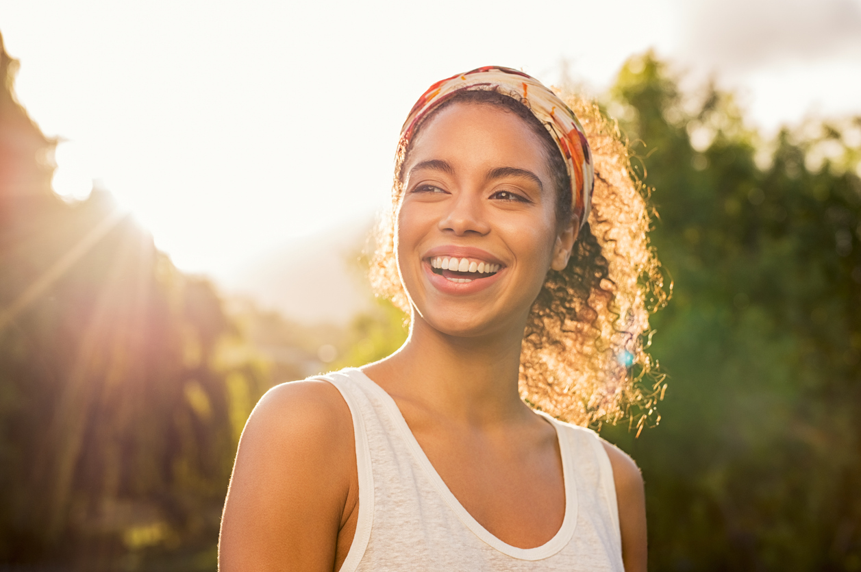 Woman smiling outdoors with natural-looking, healthy teeth in warm sunlight., Transform Your Smile with Lumineers: Your Guide from a Lumineers Dentist in Houston, TX