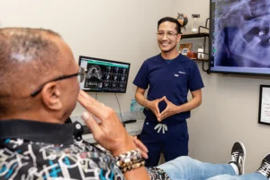 Dentist discussing dental implant options with patient while reviewing jaw scan in Houston dental office