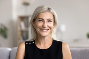 Woman with gray hair smiling confidently, with an even, bright smile.